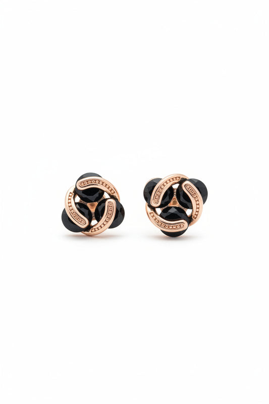 Pair of delicate rose gold interlocking stud earrings with glossy black stones held between fingers for size reference.

