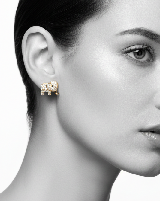 A pair of gold-plated elephant stud earrings fully encrusted with brilliant white cubic zirconia stones, displayed beautifully on a black fabric background.
